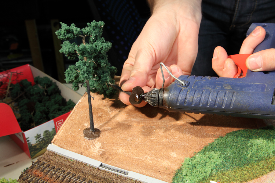 Kiefer mit Heißklebepistole auf Diorama befestigen